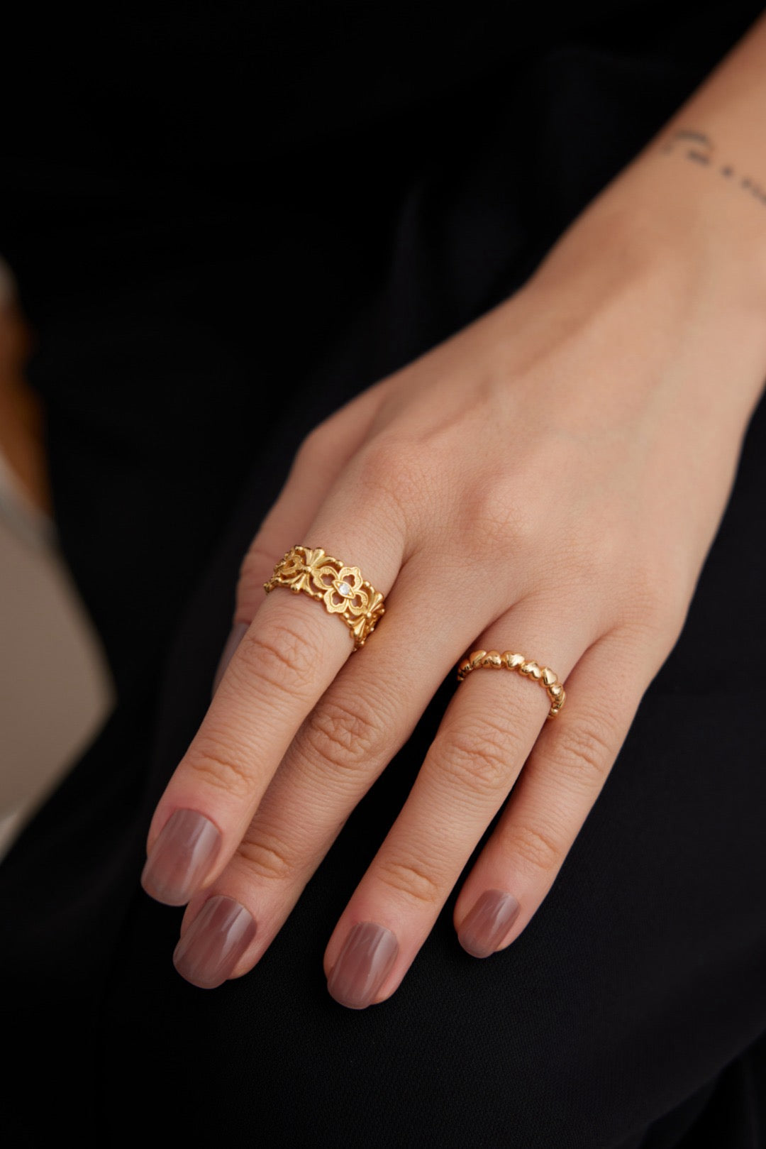 The Hollow Zircon Open Ring showcases an intricate lattice of delicate floral motifs and scrollwork wear by a woman in a black dress.