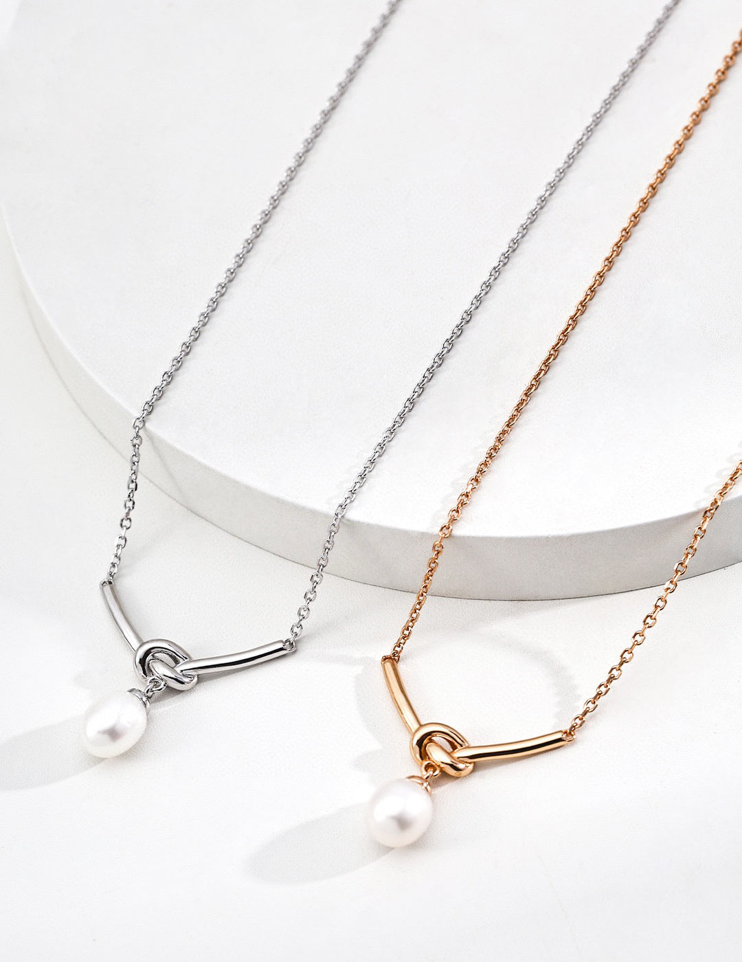 Two necklaces with pearl pendants on a white background