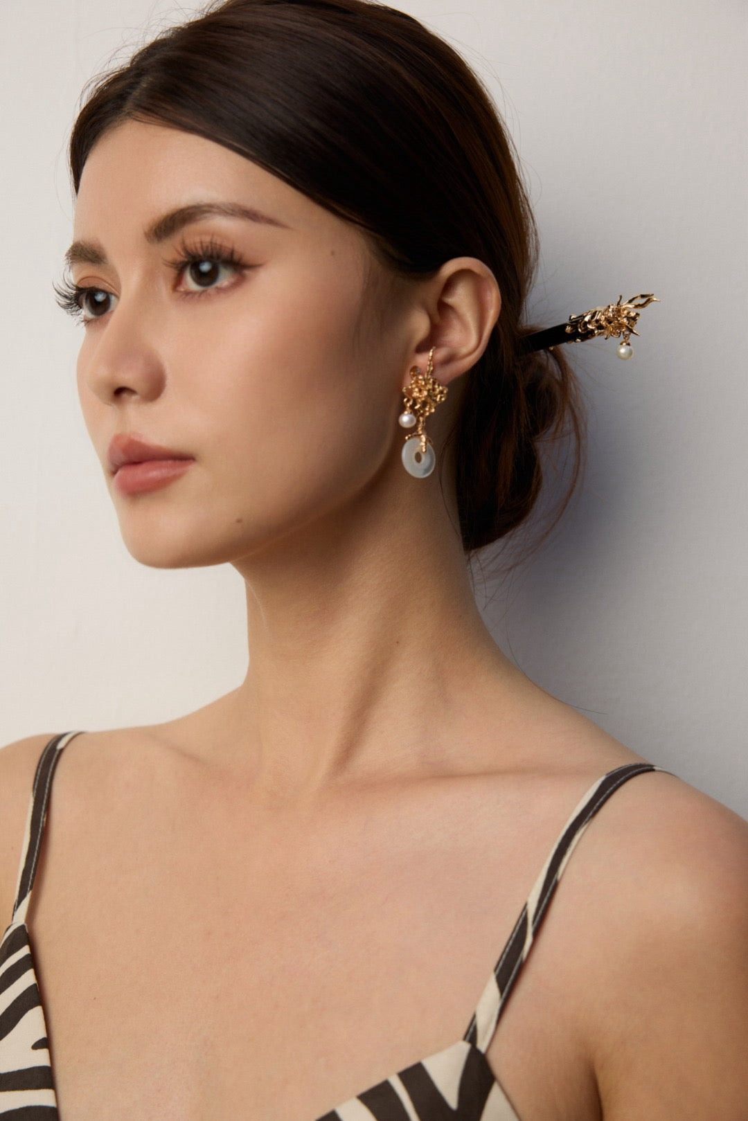 Woman wearing elegant earrings with a neutral background