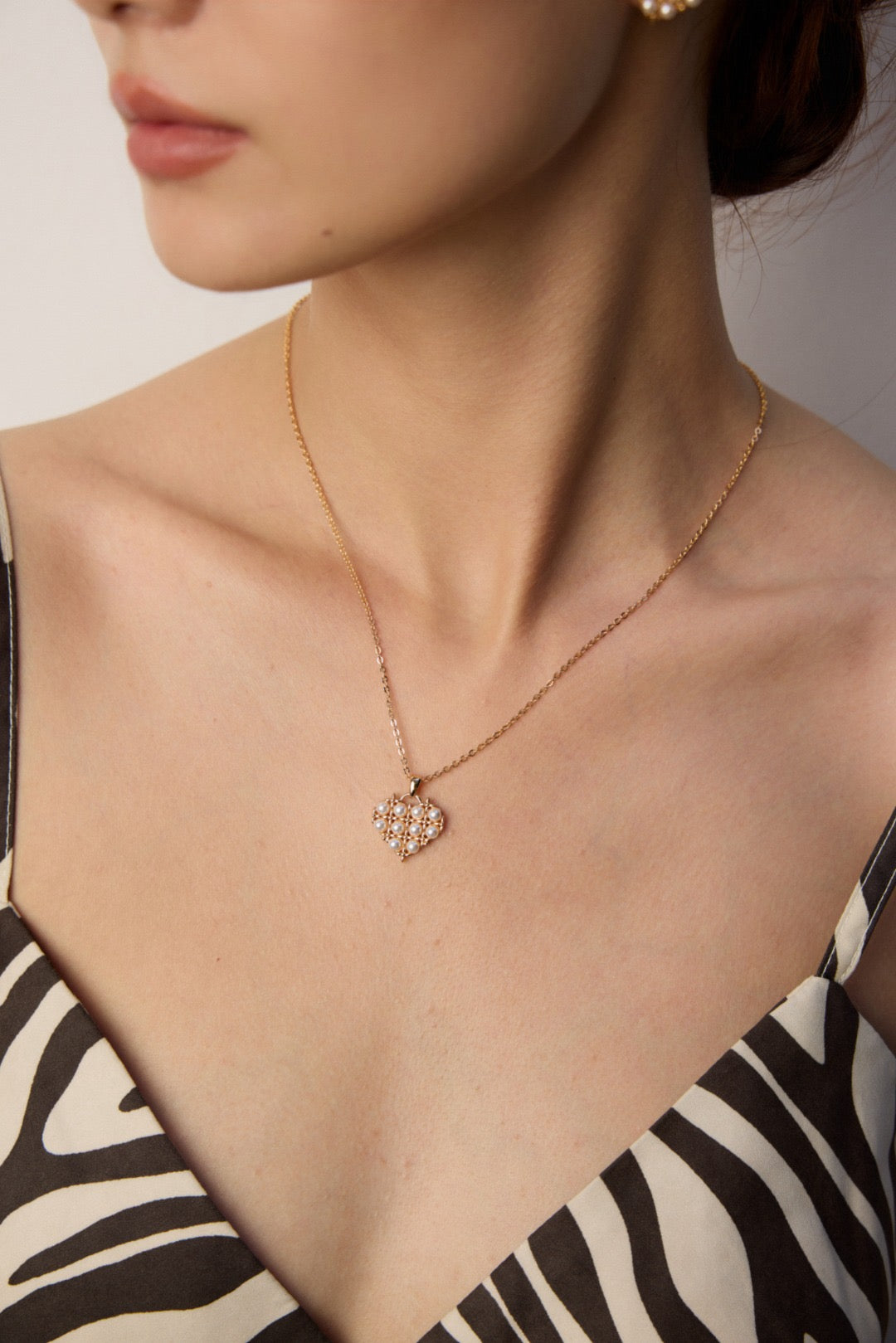 Necklace with a floral pendant worn by a person against a neutral background