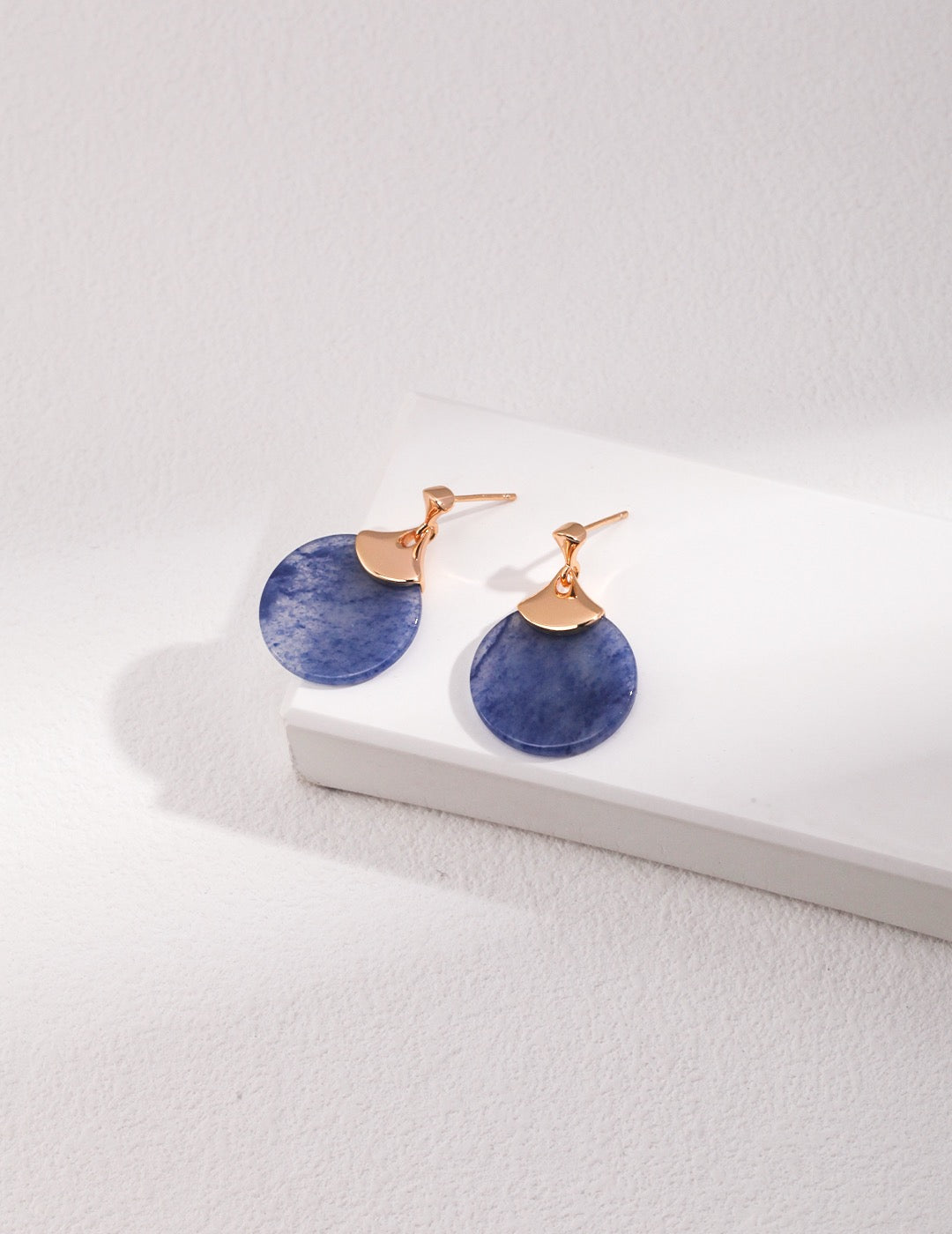 Pair of blue earrings with rose gold accents on a white surface