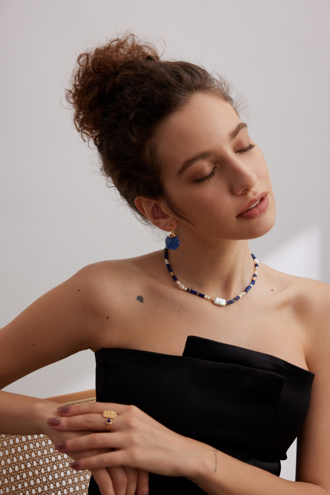 Woman wearing a black strapless dress with a white background, style with Celestial Shoreline Necklace and Indigo Moon Drop Earrings