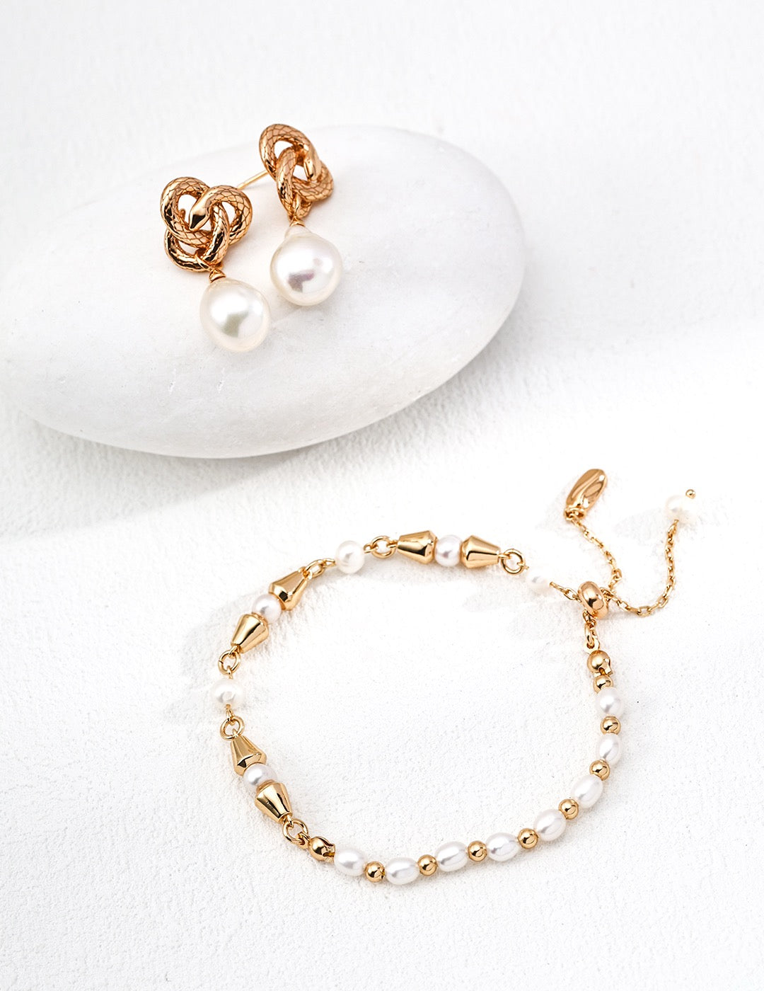 Pearl bracelet and earrings set on a white background