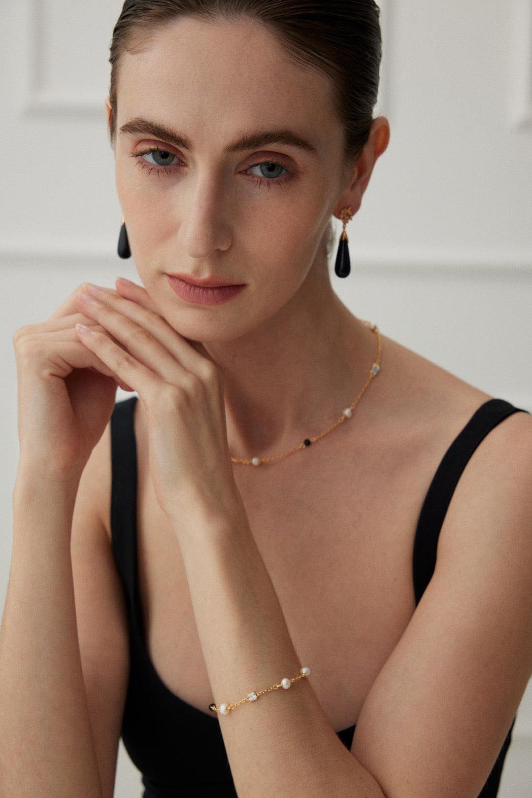 A model wears the Isla 18K Gold Freshwater Pearl Zircon Black Agate Bracelet and Necklace
