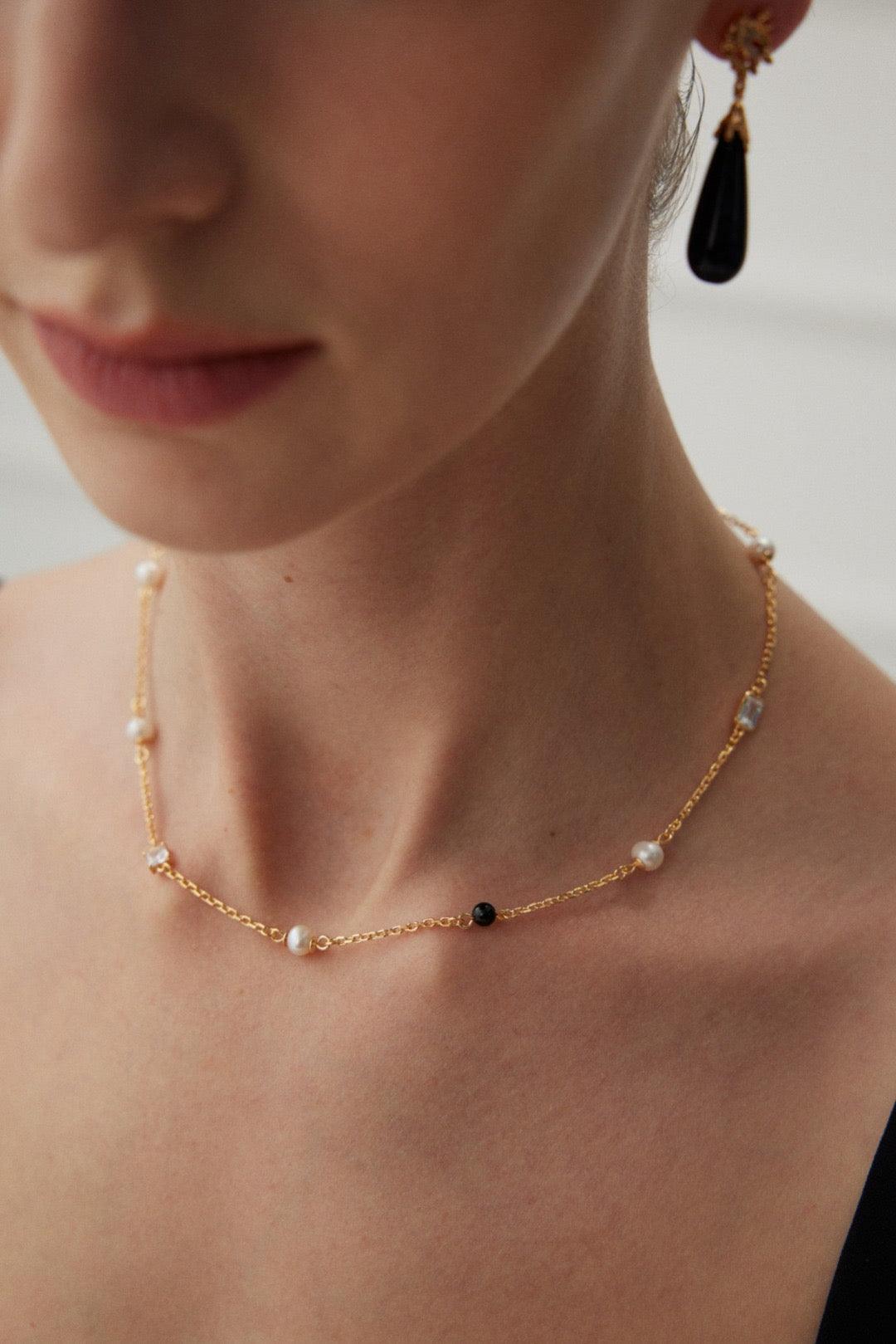 A close-up of the Isla 18K Gold Freshwater Pearl Zircon Black Agate Necklace
