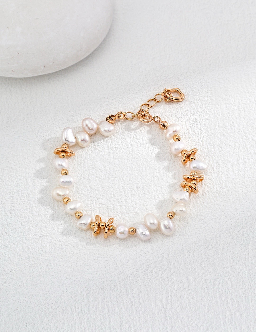 The Ivy Pearl Bracelet is displayed on a white background, showcasing the lustre of the pearls and the gold beads.