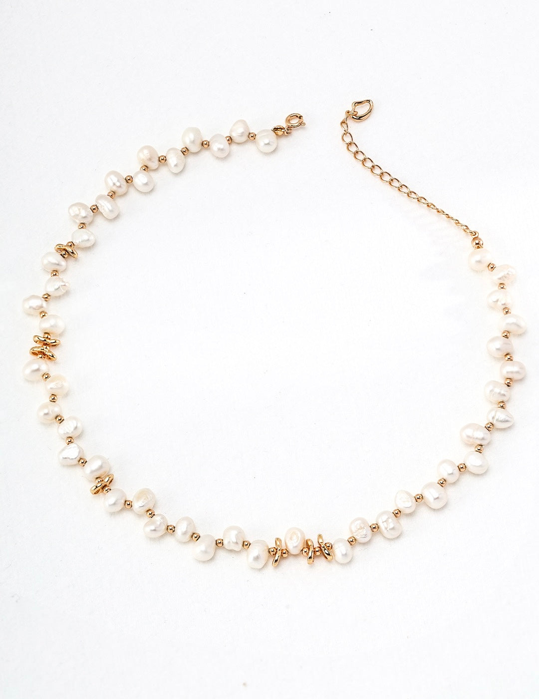 featuring a delicate necklace and matching bracelet with irregular pearls and gold-toned accents, styled on a soft white textured background.