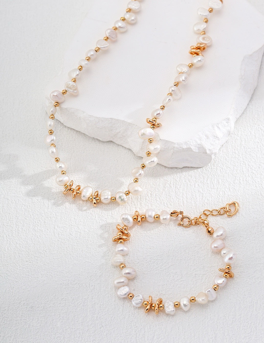 Flat lay of a gold and freshwater pearl jewelry set.