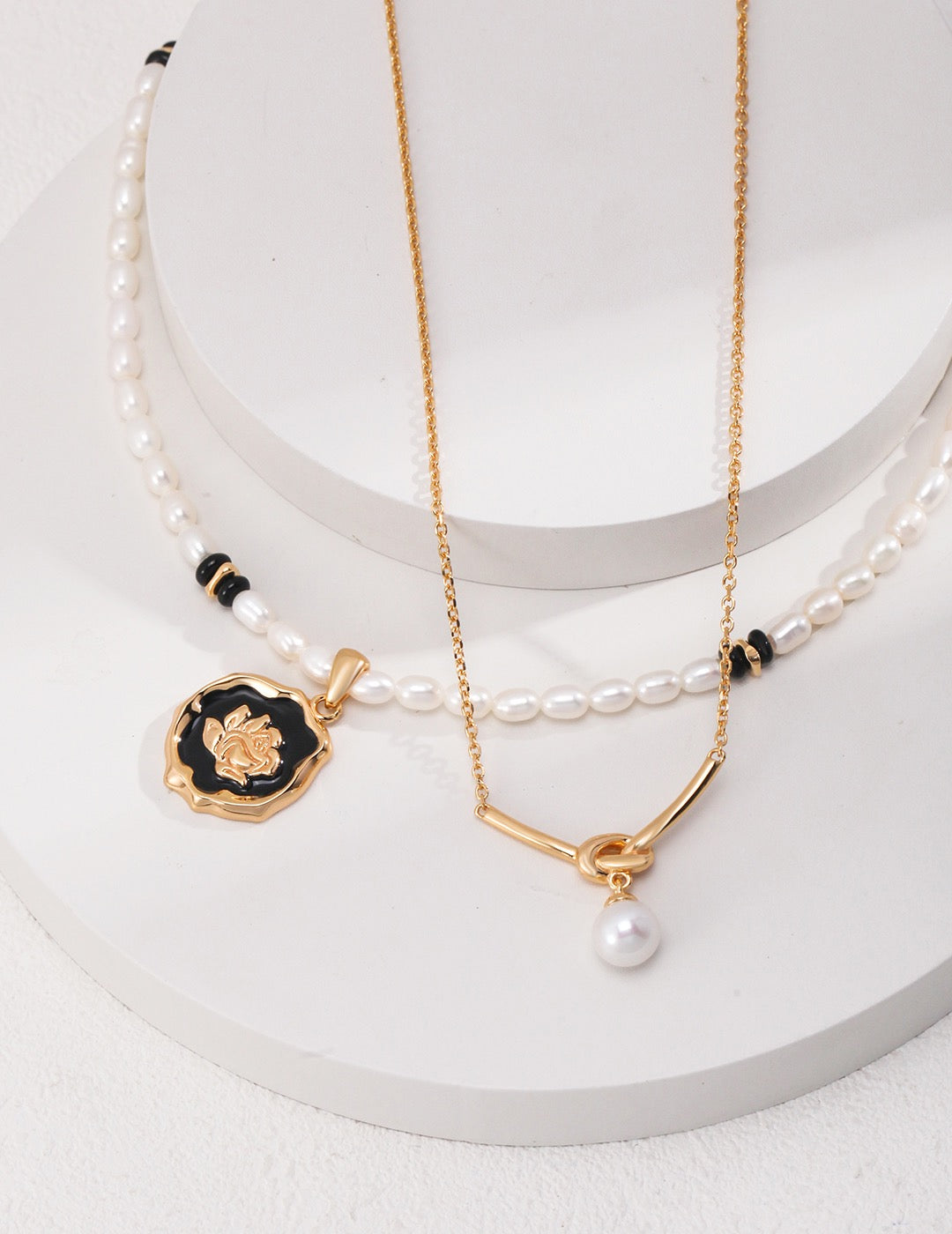 Two necklaces with pendants on a white surface