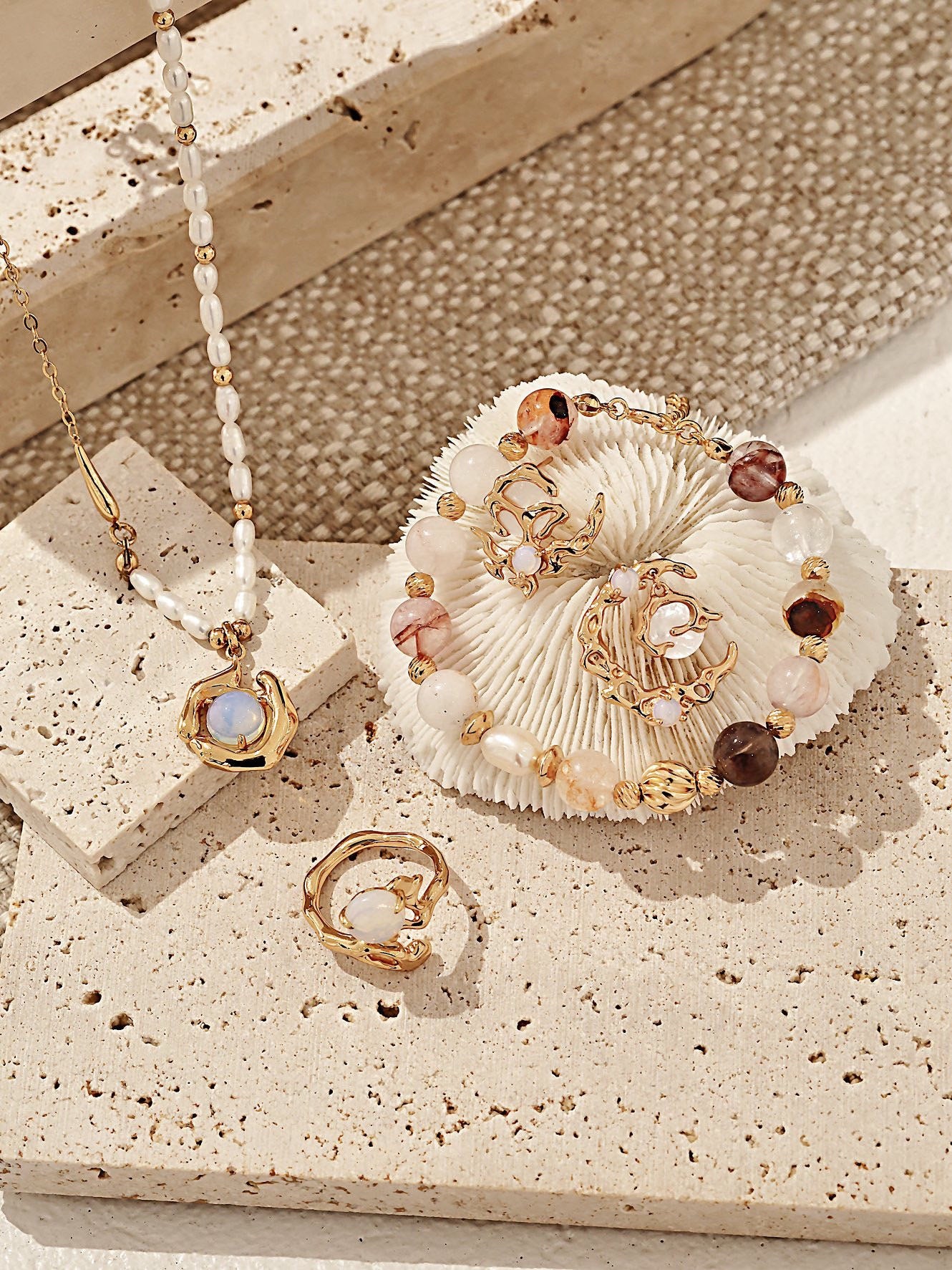 Jewelry set including a necklace, ring, and decorative item on a textured surface