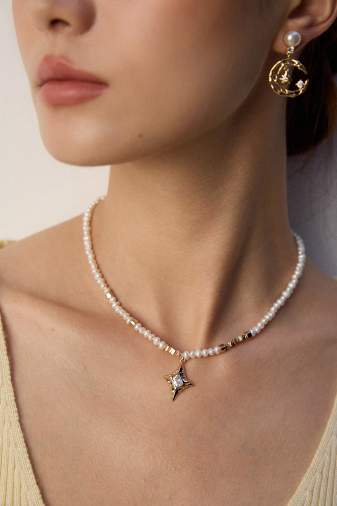 Pearl necklace with a star pendant worn by a person against a neutral background