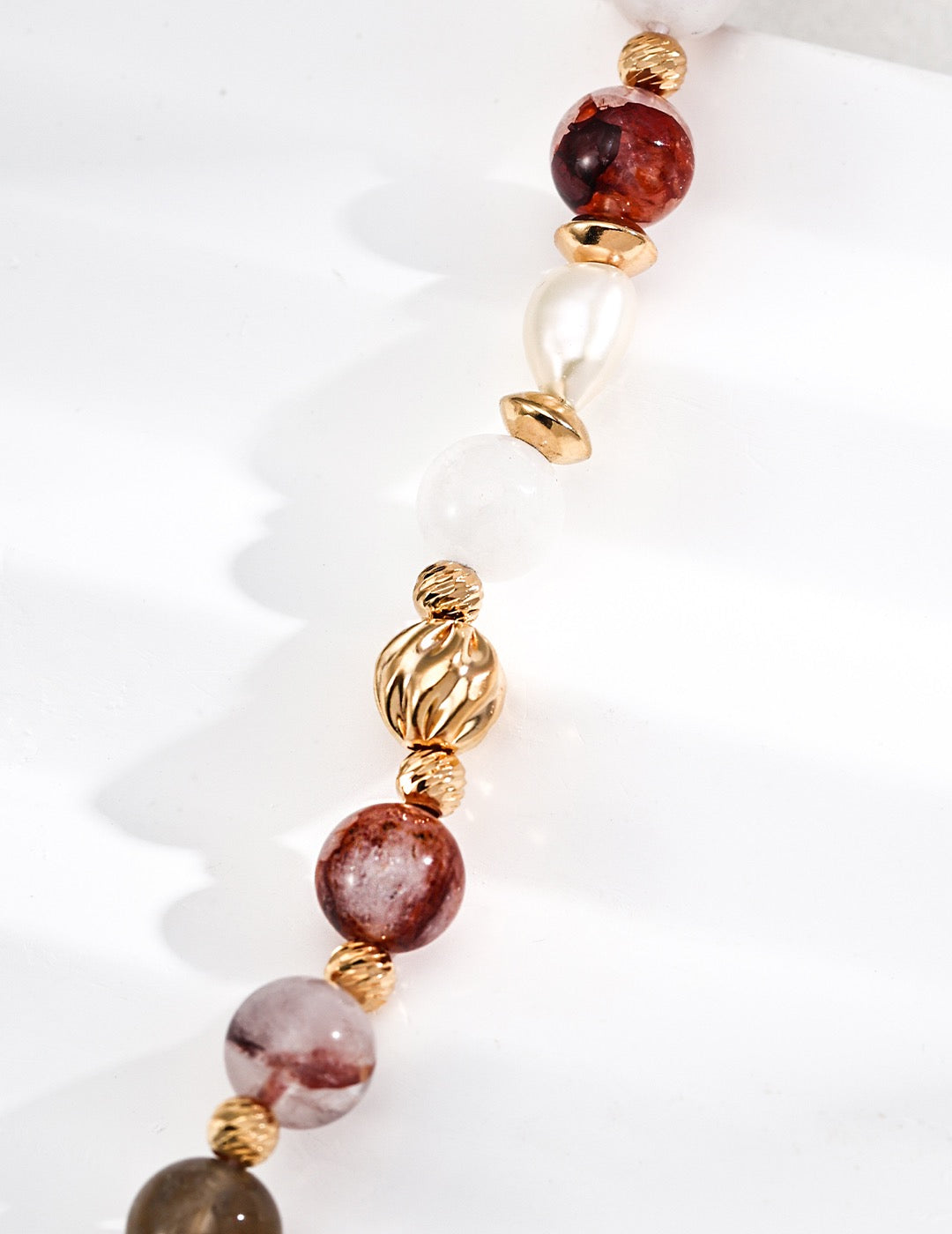 Bracelet with multicolored gemstone beads and gold accents on a white background