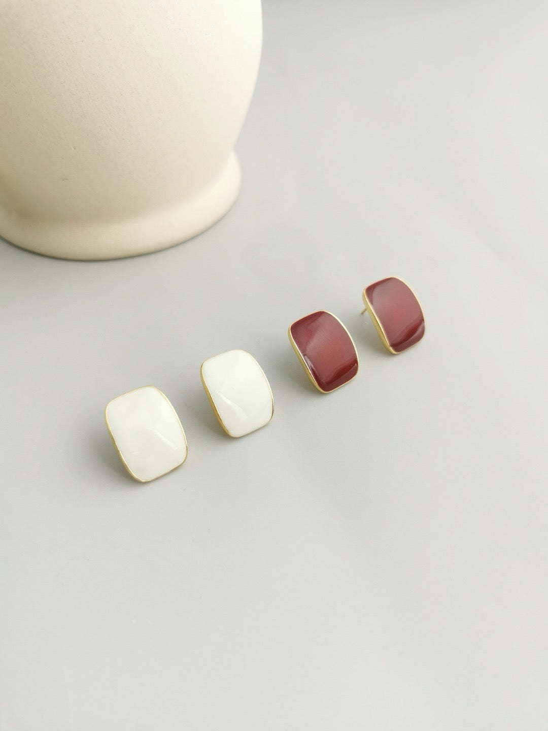 Set of four earrings with gold and red stones on a light gray background