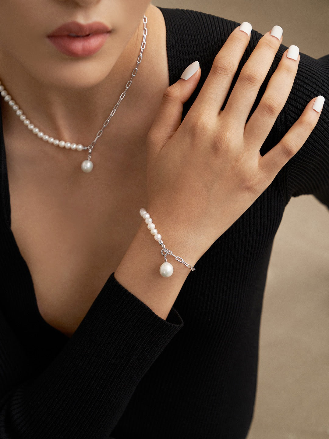 Model wearing the Luna Dual-Chain Freshwater Pearl Necklace and Bracelet set in silver. The necklace features a mix of pearls and chain with a dangling pearl charm, while the bracelet mirrors the design. Styled with a sleek black top, highlighting the jewelry's elegance.