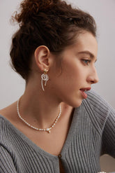 A woman wearing the Nora Earrings, which are gold vermeil with zirconia stone inlayed pearl tassel designs.