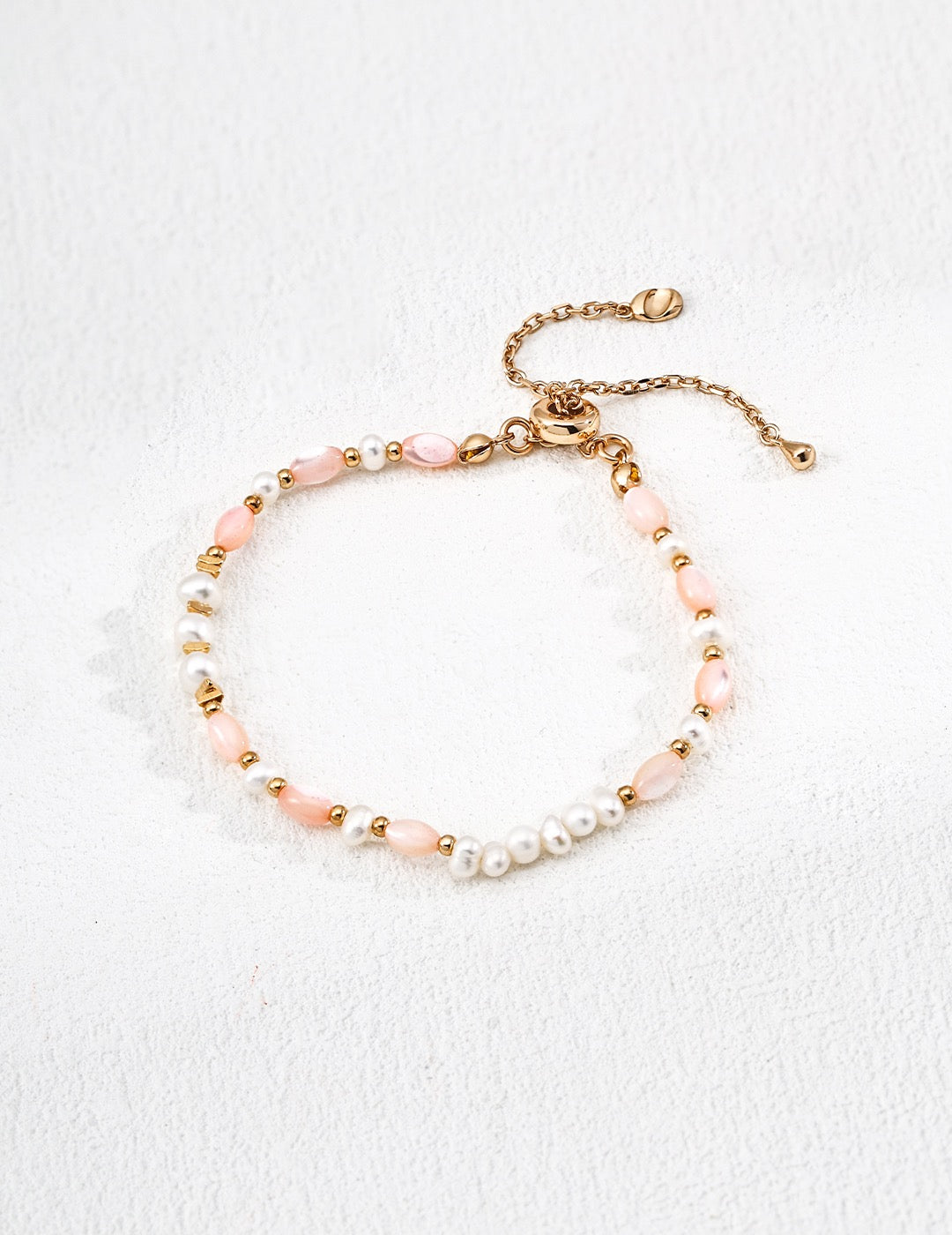 Orchid Pearl Strand featuring  pink Tridacna Stone and freshwater pearls with 18K gold vermeil accents, displayed on a white textured background.”