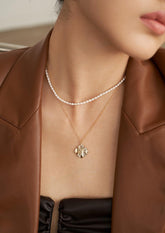 A close-up of the model is wearing the pearl-layered pendant necklace in a black dress and a brown leather jacket.