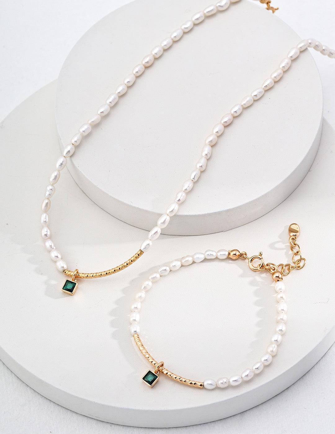 Julia Necklace and bracelet displayed on a white circle stage, showcasing the emerald-green gemstone charm.