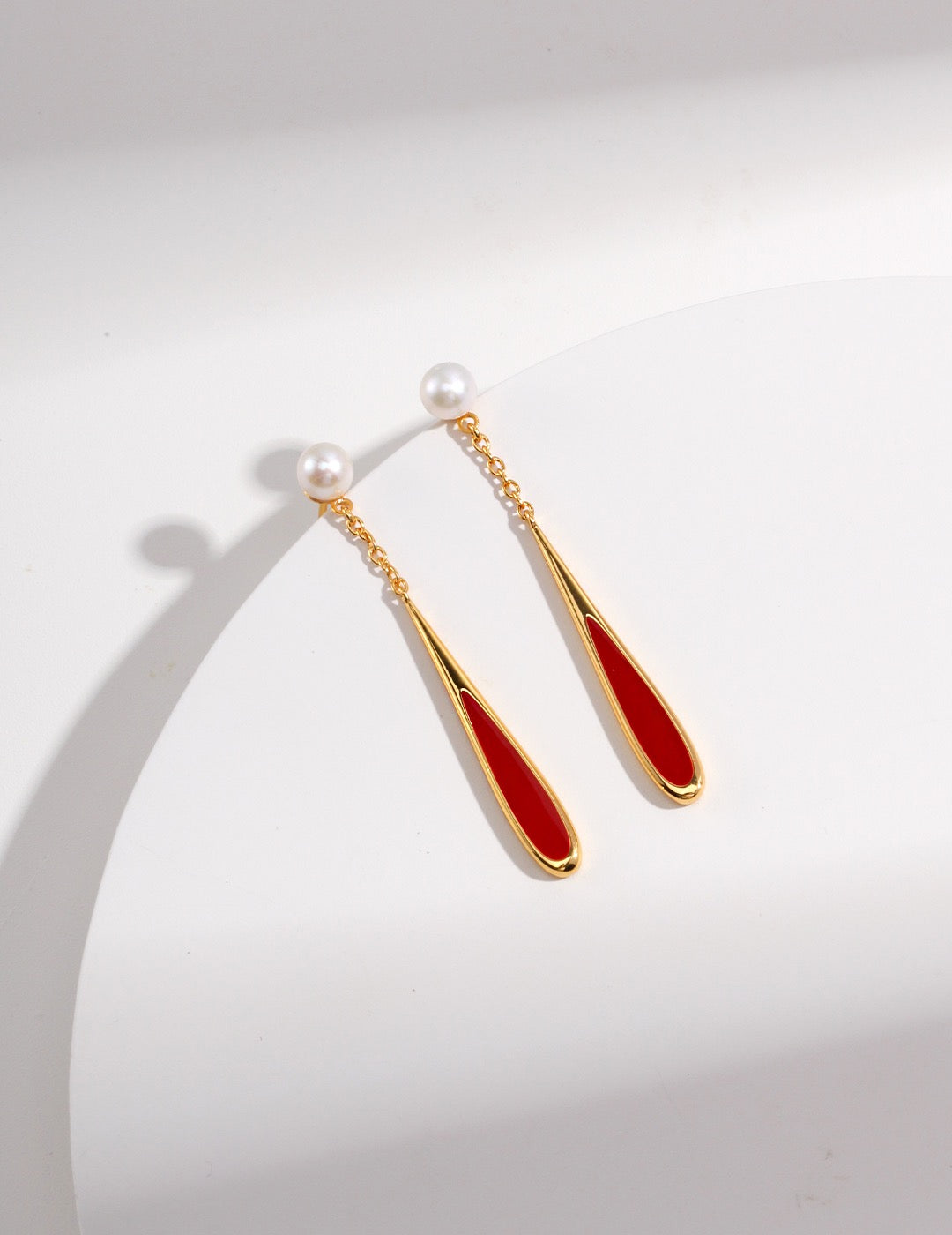 Pair of earrings with gold and red design on a white background