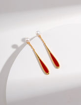 Pair of earrings with gold and red design on a white background