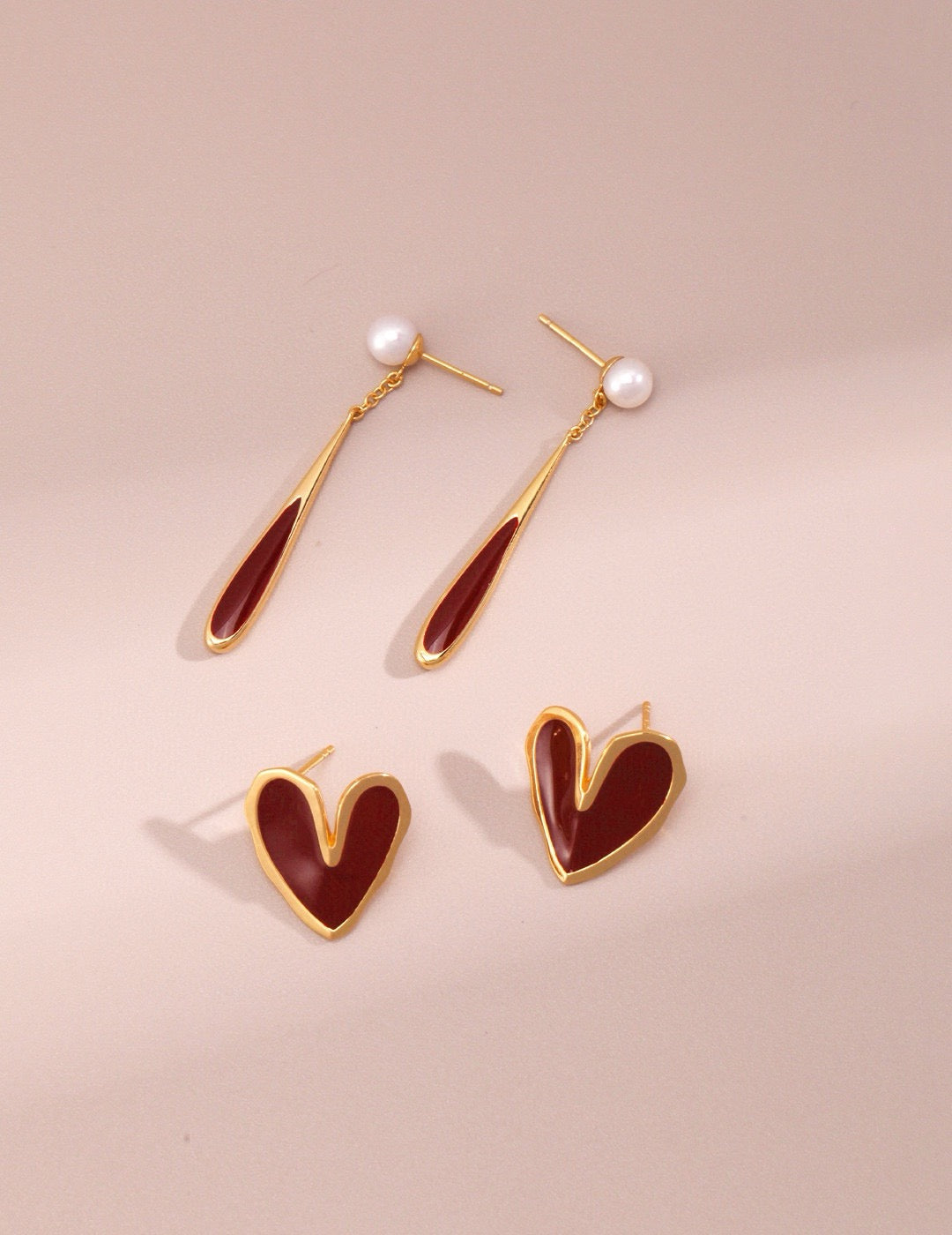 Heart-shaped earrings with gold and red design on a beige background