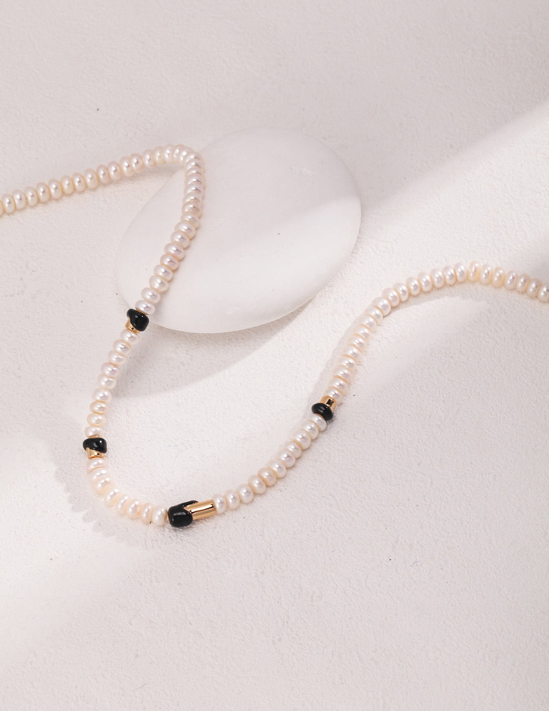 A close-up of Ceres 18K Gold Freshwater Pearl Black Enamel Necklace, focusing on the elegant design.