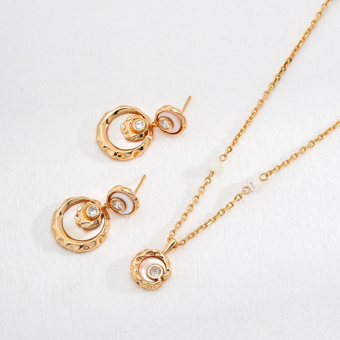 Close-up of gold Rayna Set necklace and earrings displayed on the white surface