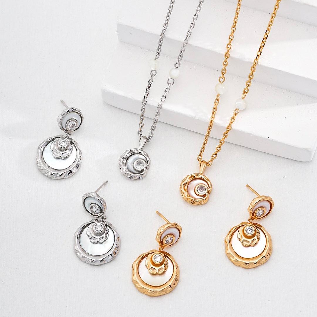 Silver and gold Rayna Necklace Sets with earrings displayed on a white stage - Lia Atelier
