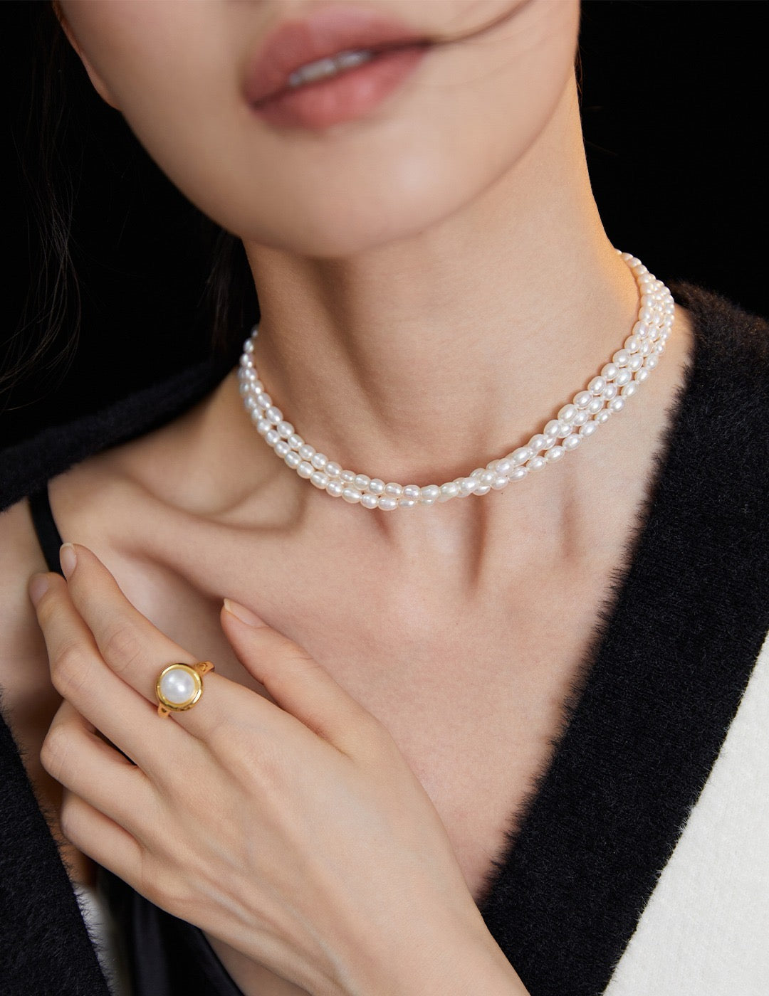 Triple Strand Pearl Choker Necklace and ring on a person against a black background