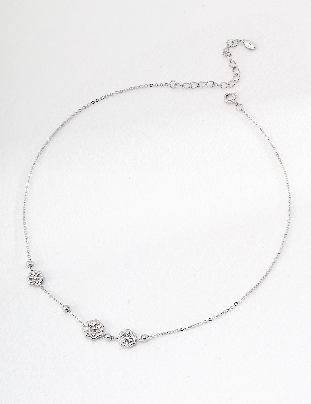 Sterling Silver Floral Charm Necklace displayed on a white surface, minimalist and perfect for layering.