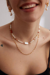 A person wearing a Strawberry Quartz Necklace with gold vermeil chain and pearl details.