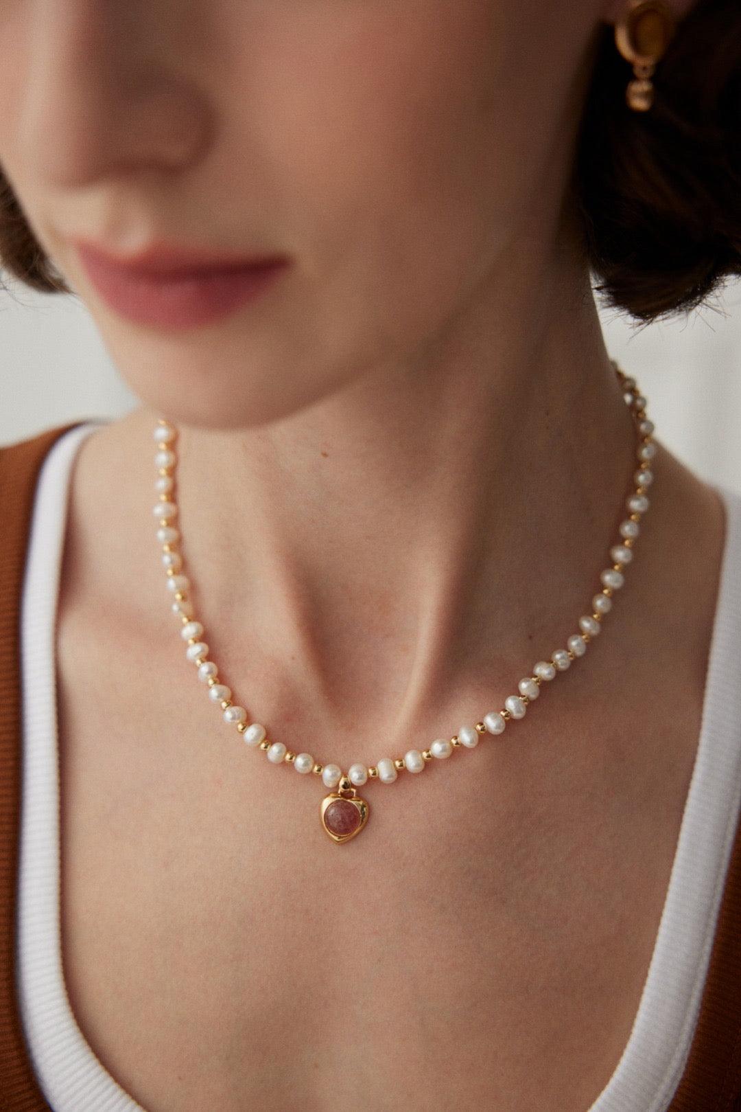 A person wearing a Strawberry Quartz Pearl Necklace with gold vermeil detailing.