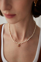 A person wearing a Strawberry Quartz Pearl Necklace with gold vermeil detailing.