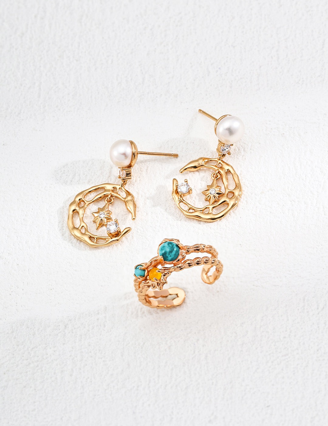 Pair of gold earrings with star and moon designs on a white background