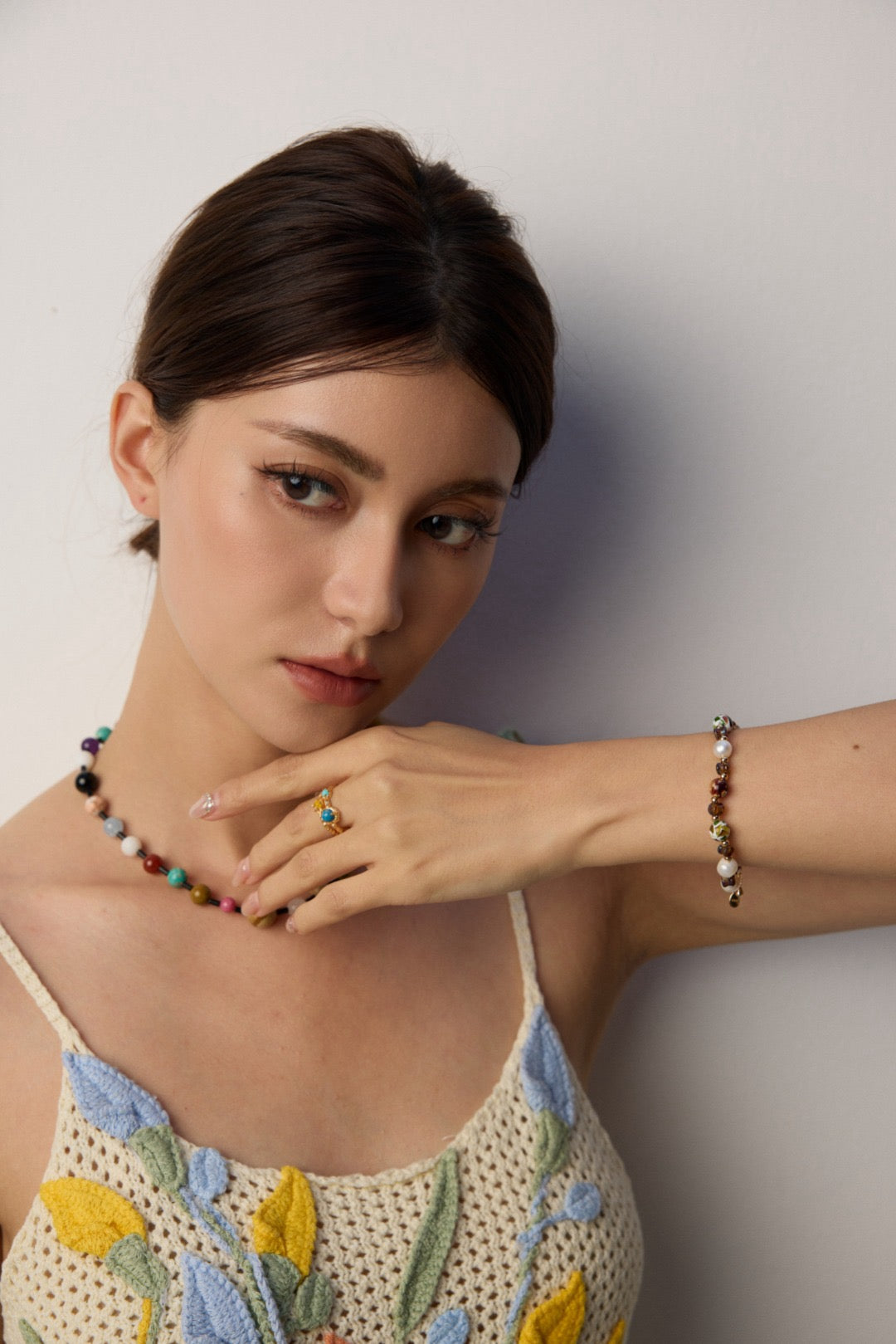 Woman wearing a floral dress with jewelry against a plain background