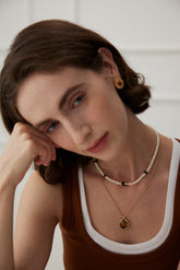 A women wear the tiger's eye pendant necklace layering with the pearl strand necklace.