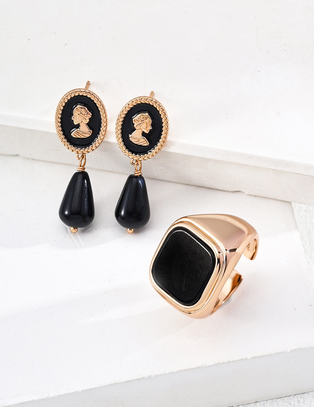 Pair of black teardrop earrings with gold accents on a white surface