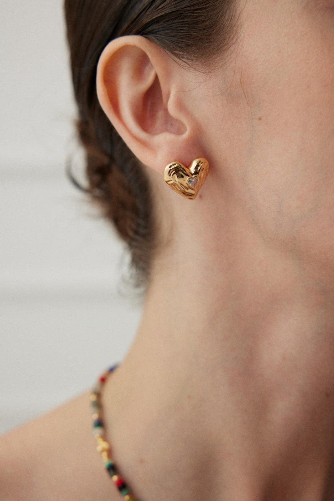 A close-up of the Gold Zircon Heart Shape Stud Earrings worn by the model.