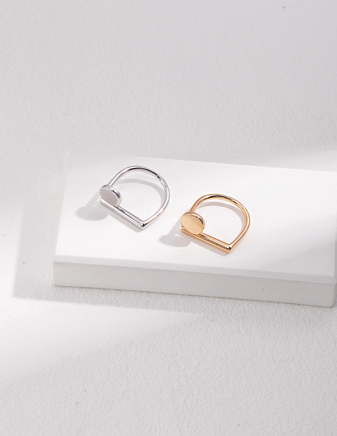 A gold and silver geometry Open Ring displayed on the white rock.