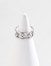 A close-up of the sterling silver open ring with a floral design adorned with small freshwater pearls, displayed on a white cone-shaped jewelry holder against a clean white background.
