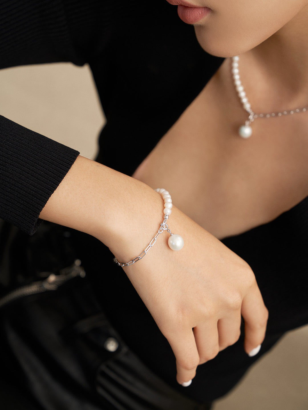 Different angle of the model wearing the Luna Dual-Chain Freshwater Pearl Necklace and Bracelet set in silver. The necklace features a mix of pearls and chain with a 10.5mm pearl pendant, while the bracelet mirrors the design. Styled with a sleek black top, highlighting the jewelry's elegance.