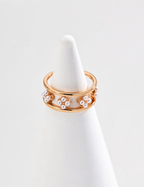 A close-up of the 18K Gold open ring with a floral design adorned with small freshwater pearls, displayed on a white cone-shaped jewelry holder against a clean white background.