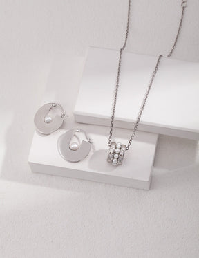 Silver necklace and earrings on a white stand with a light gray background