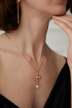 A side view of the model is wearing the Gold Pearl Pendant Necklace with the black deep v dress. 