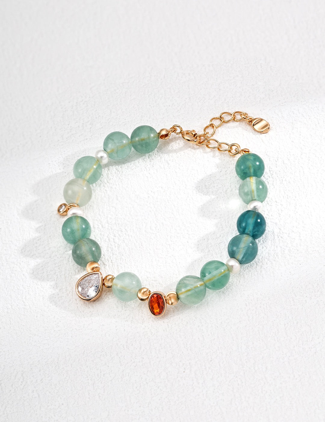 Bracelet with green gemstones and gold accents on a white background