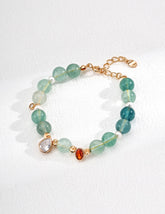 Bracelet with green gemstones and gold accents on a white background