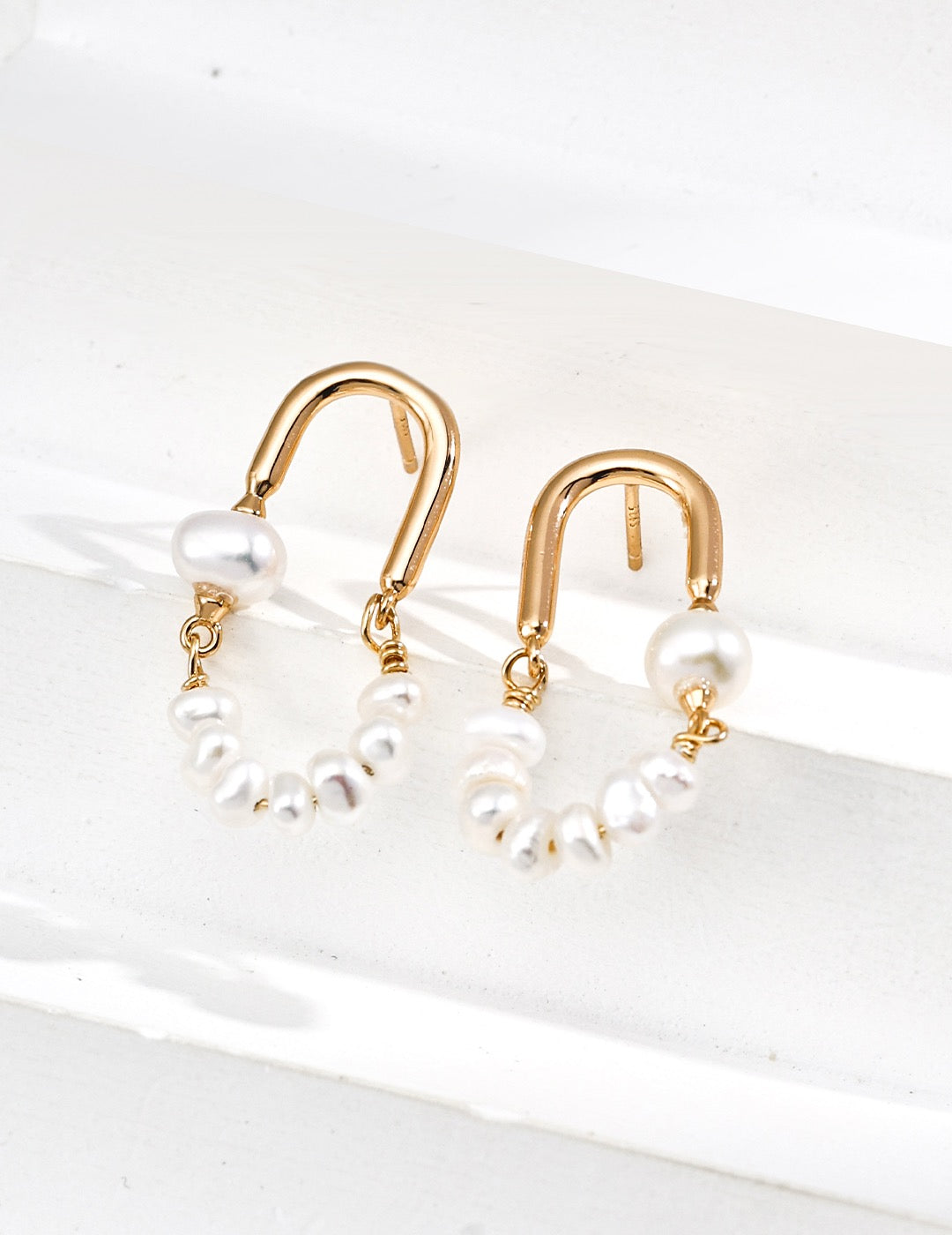 Arc of Pearls Hoop Earrings displayed on the white stairs 