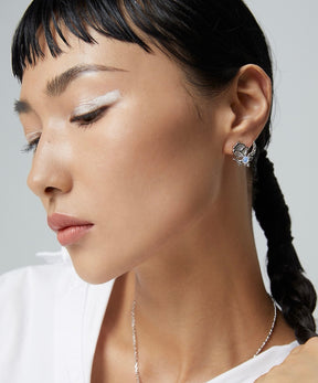 Close-up of a woman wearing asymmetrical butterfly earrings with a neutral background