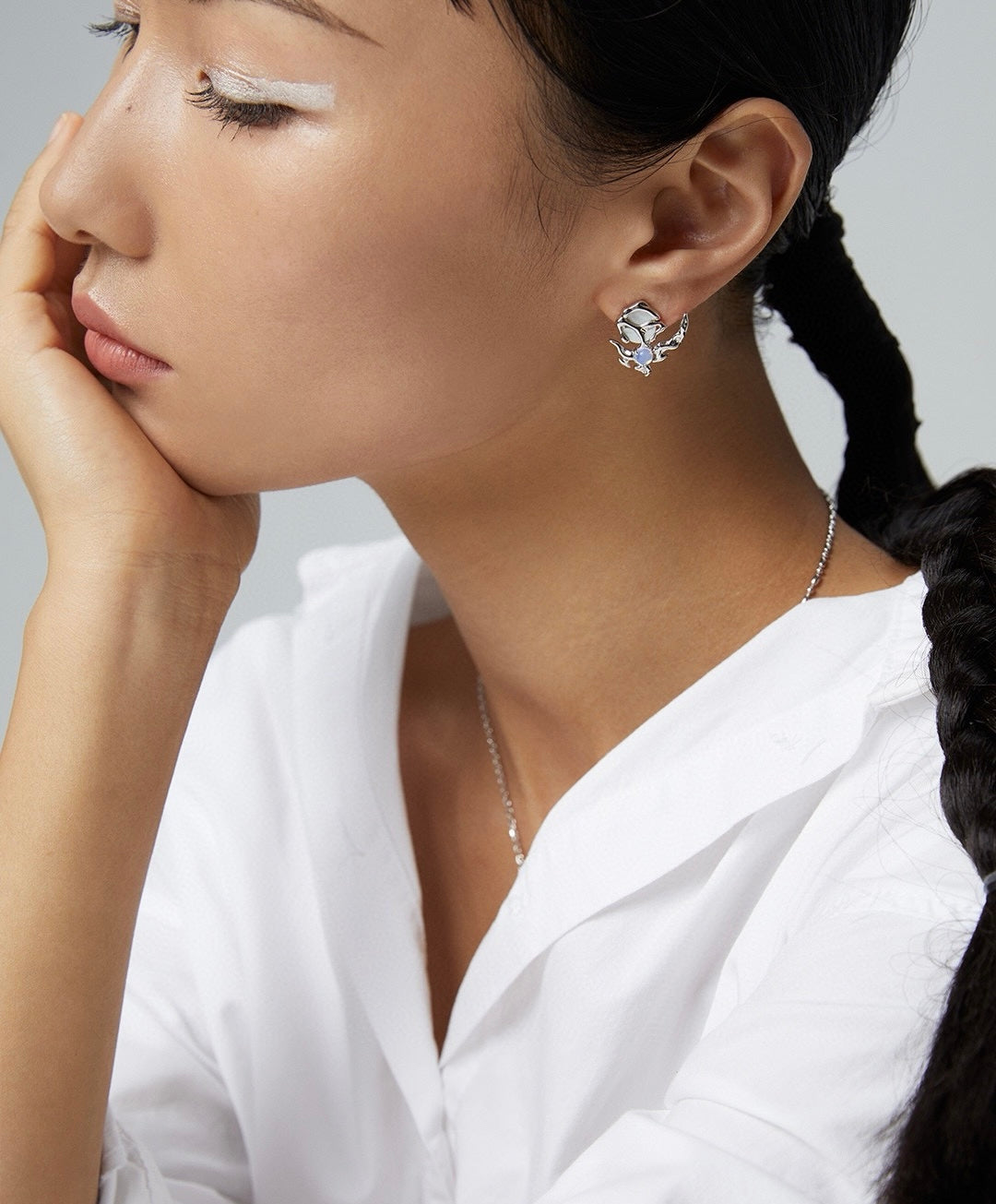 Woman wearing silver earrings and necklace with a white background