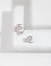 Pair of asymmetrical silver earrings with gemstones on a white background